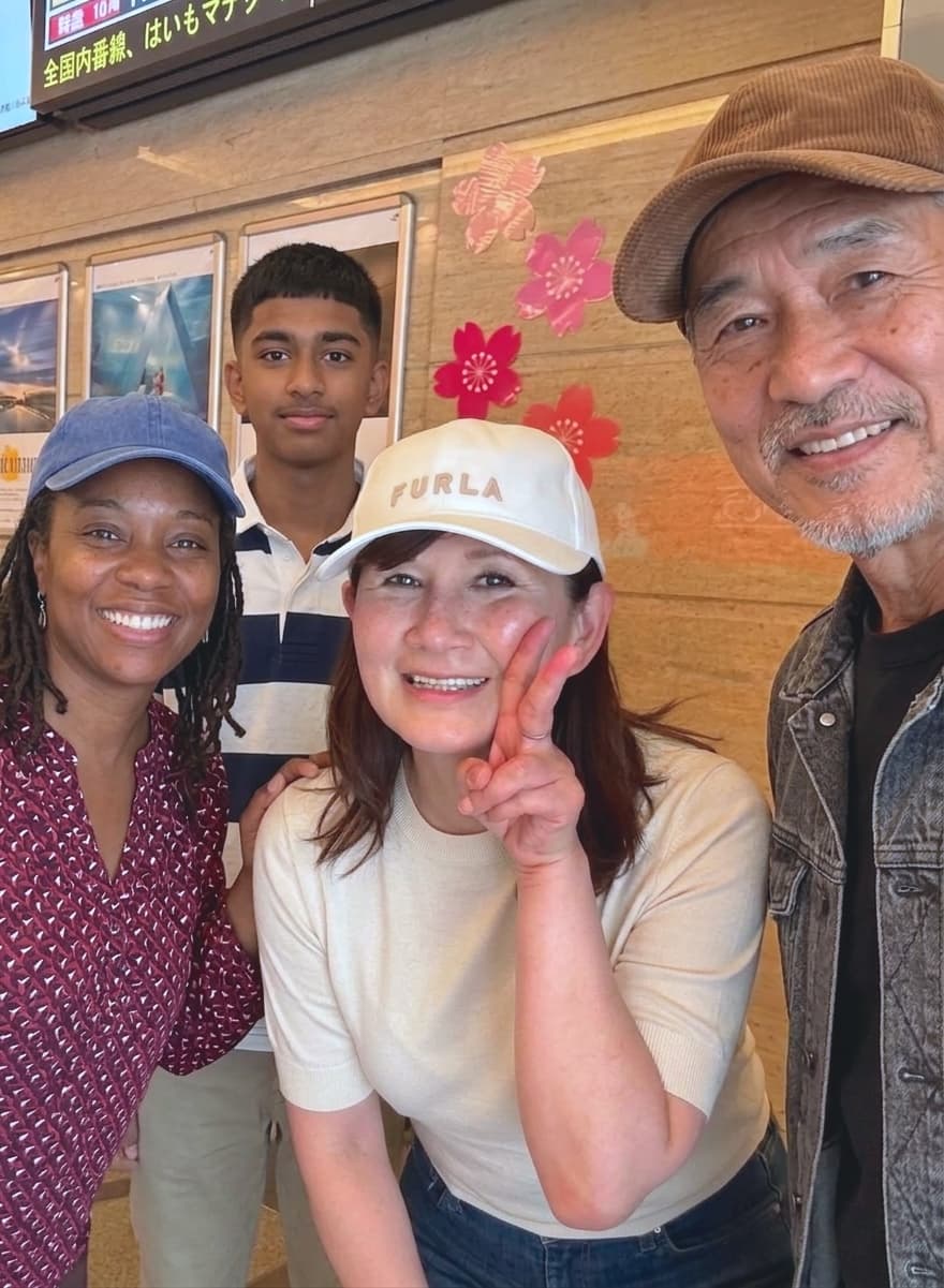 a guide and three guests close together in a station, one peace sign up