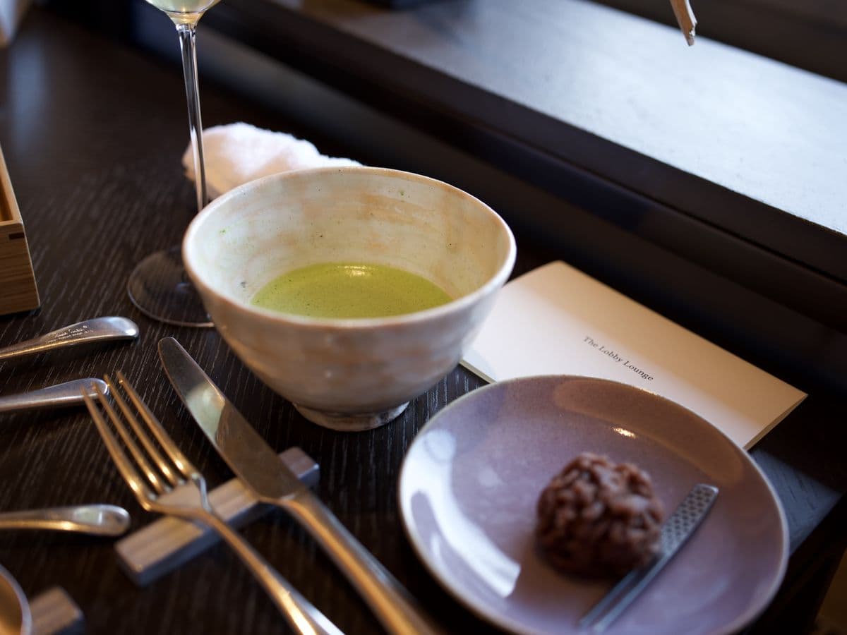 a bowl of matcha and a sweet on a dark wooden table