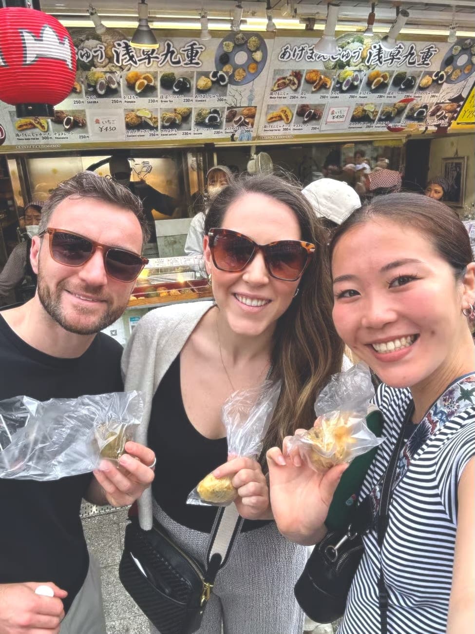 a guide and her two guests holding warm manju at the stand