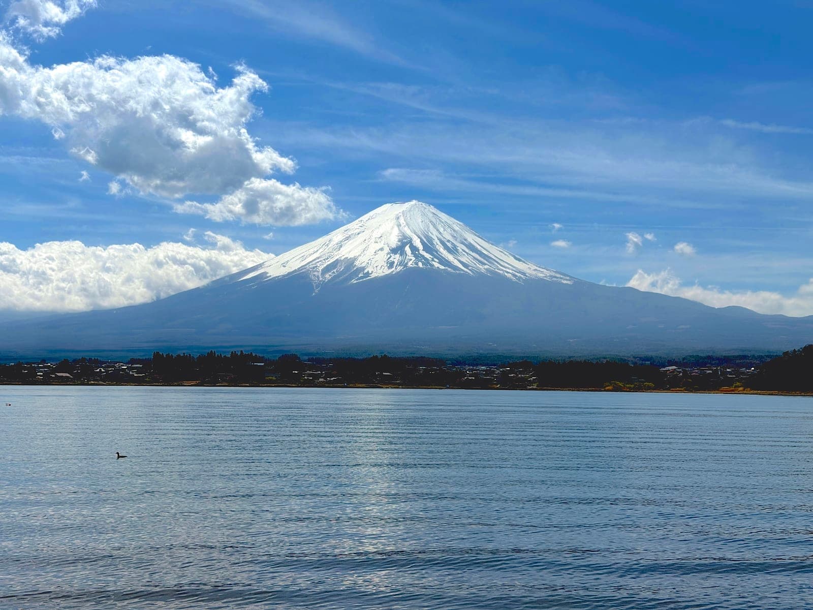 snow-capped Mount Fuji across open water under a blue sky