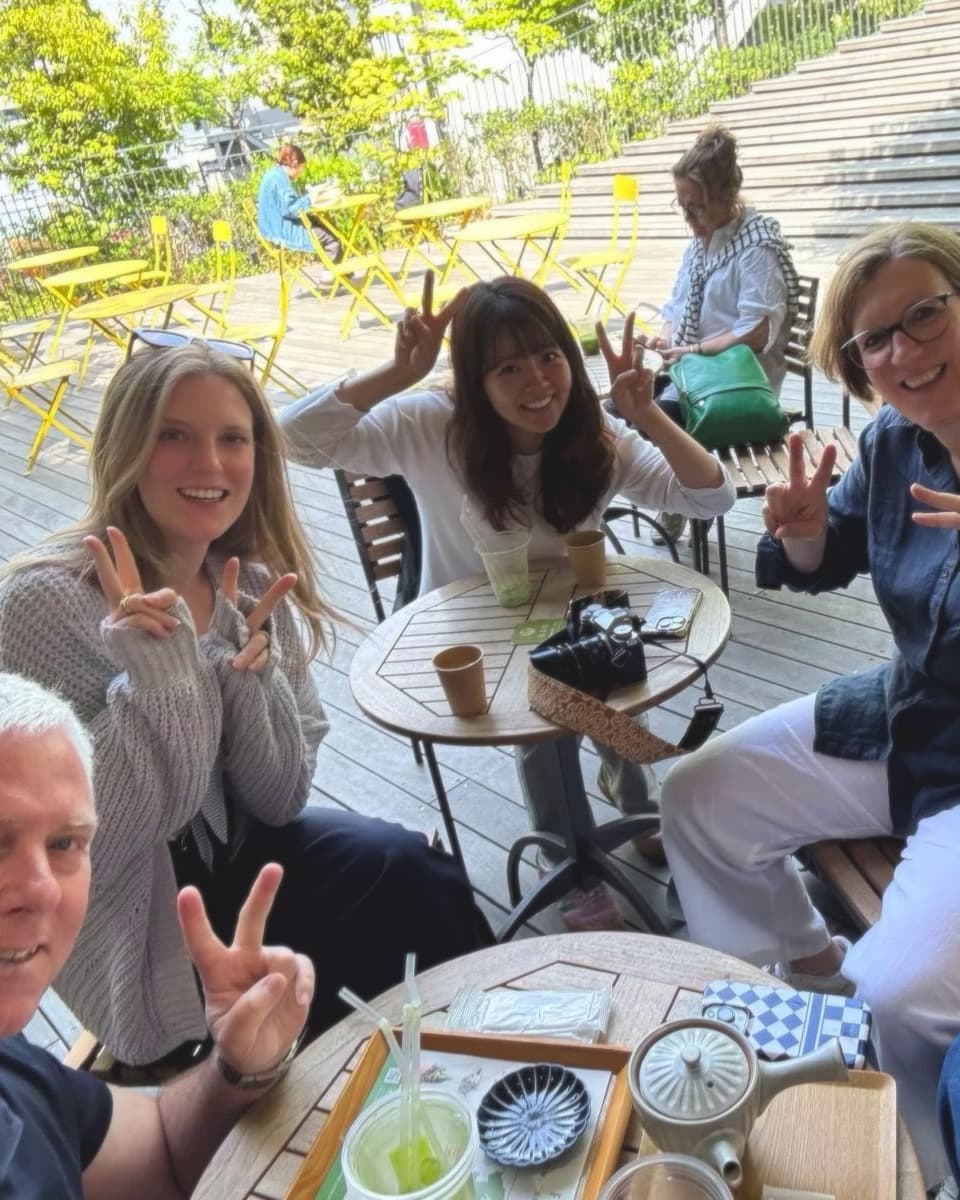 a guide and her guests around terrace tables, teapot out, peace signs up