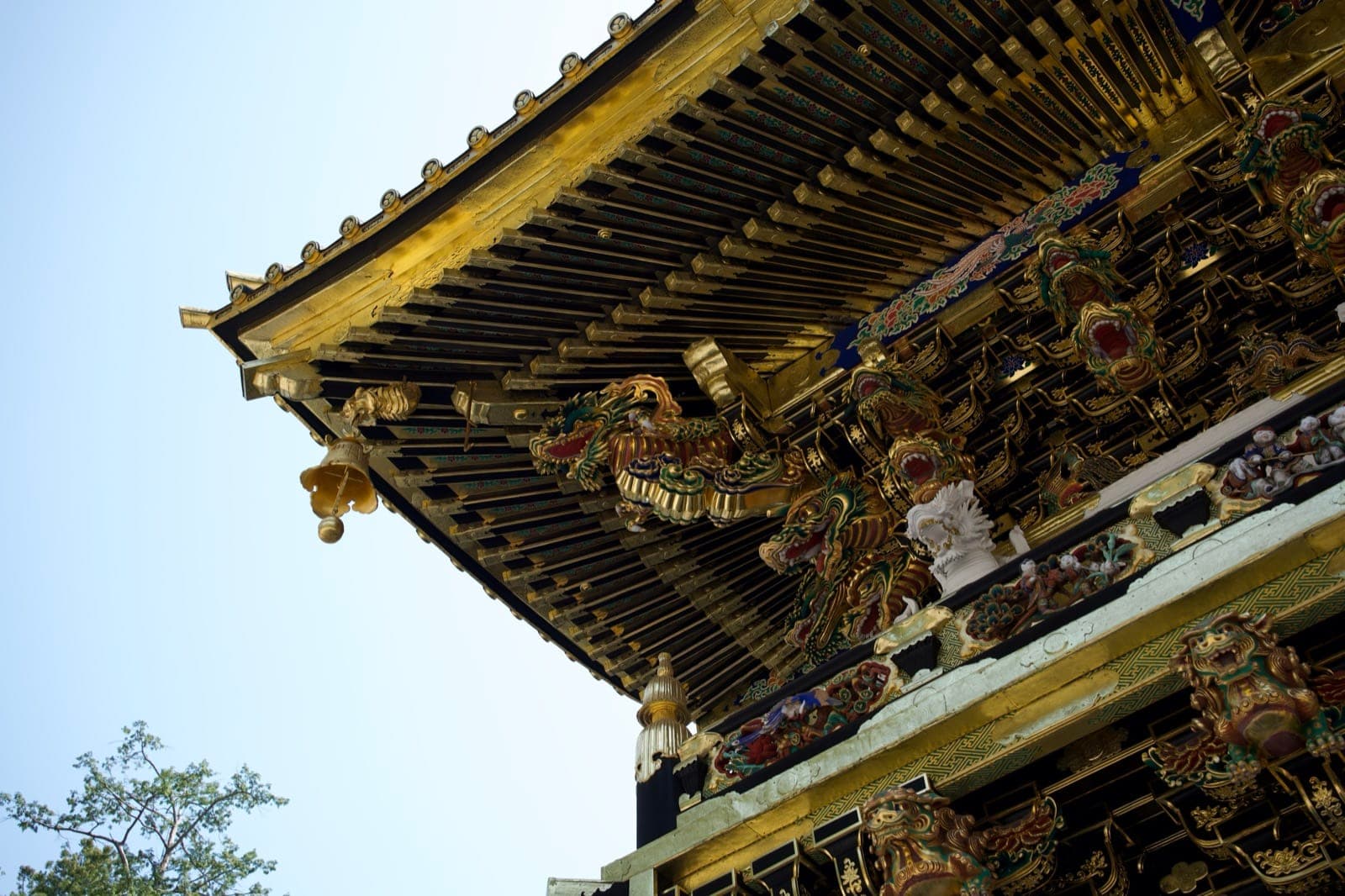 gilded eaves and painted dragon carvings of the Yomeimon gate, seen from below against the sky