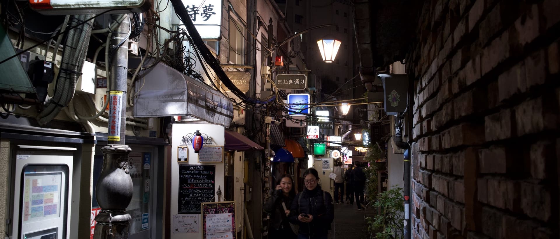 a lit bar doorway in a dark Golden Gai lane