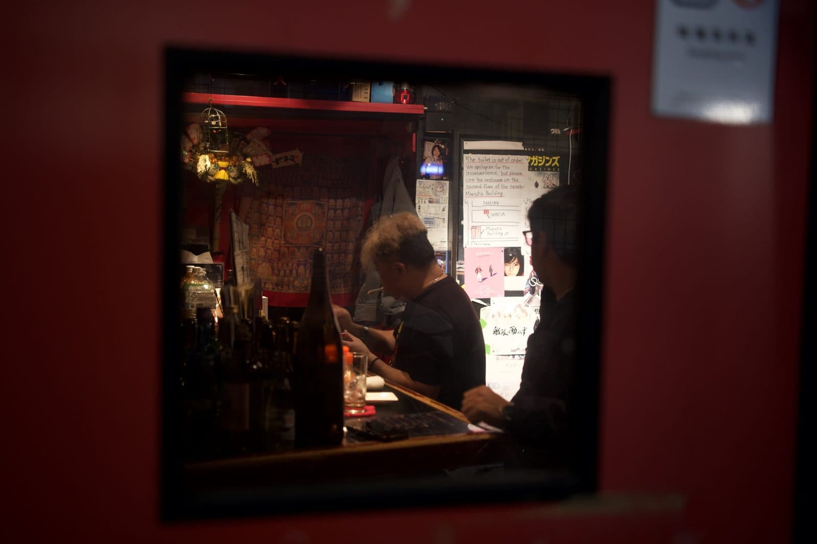 a bar interior seen through a red window frame