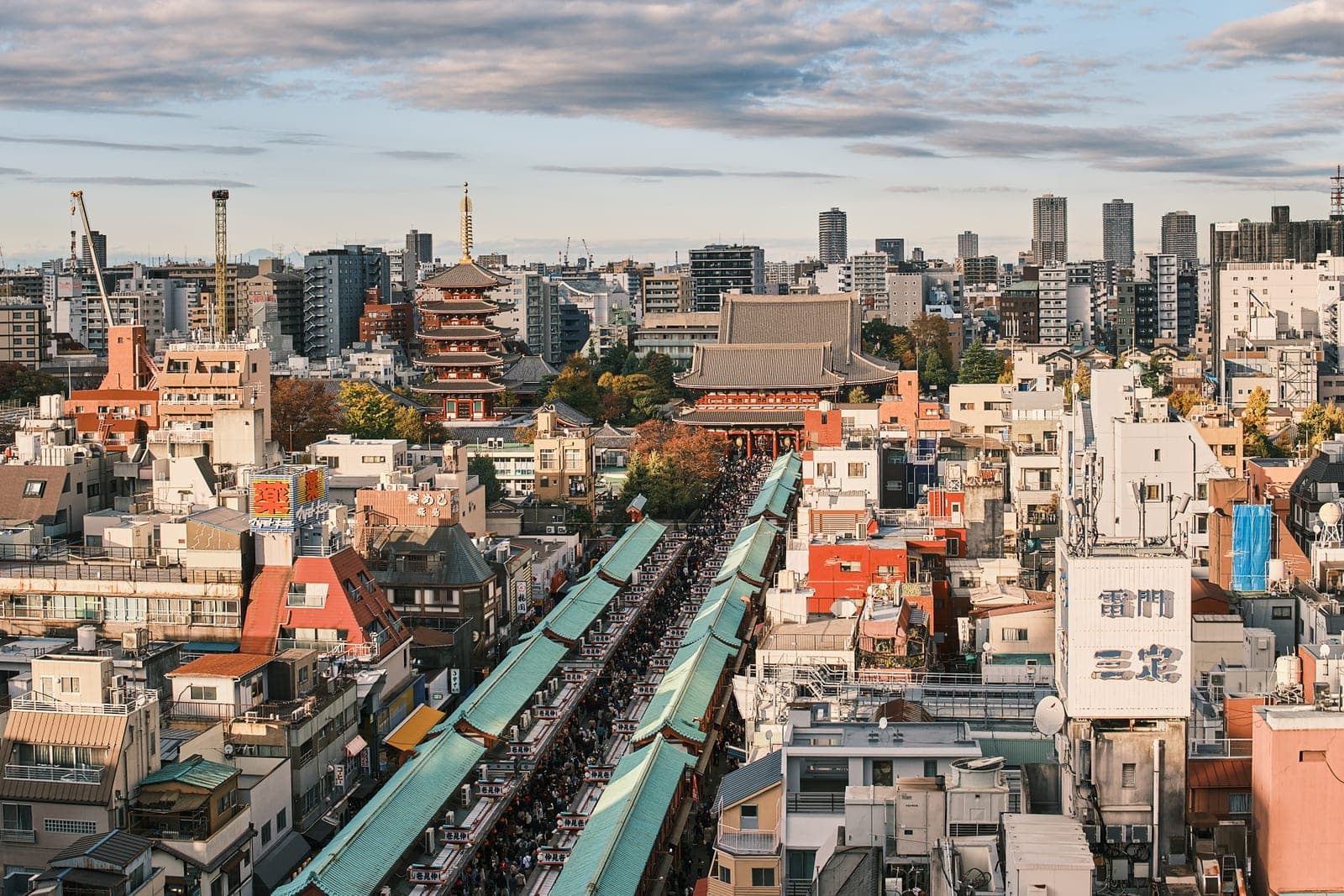 Nakamise's covered arcade running to Senso-ji's gate and pagoda, the city skyline behind