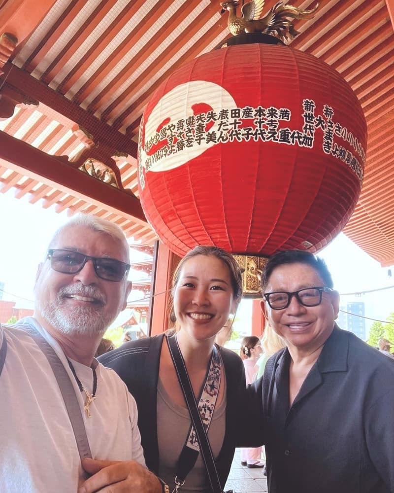 a smiling guide under the great lantern at Senso-ji, her two guests beside her